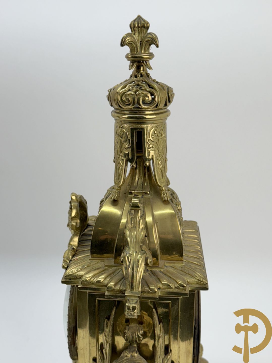 Driedelige bronzen vergulde garntiuur bestaande uit klok met medusahoofden en sfinxen, geflankeerd door paar zevenarmige kandelaars met accanthusranken en sfinxen