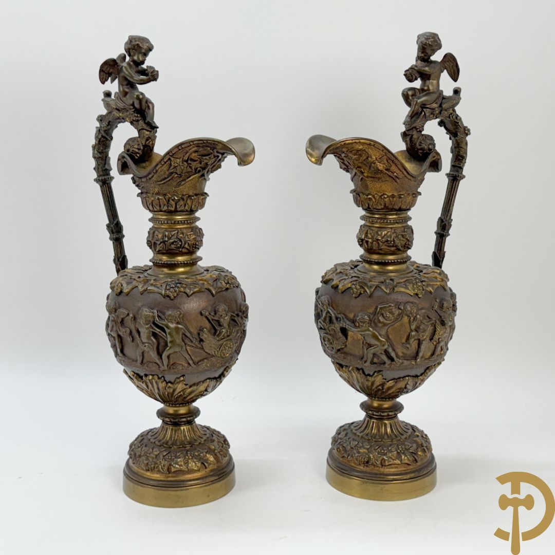 Paar bronzen schenkkannen met basrelief van putti en accanthusranken