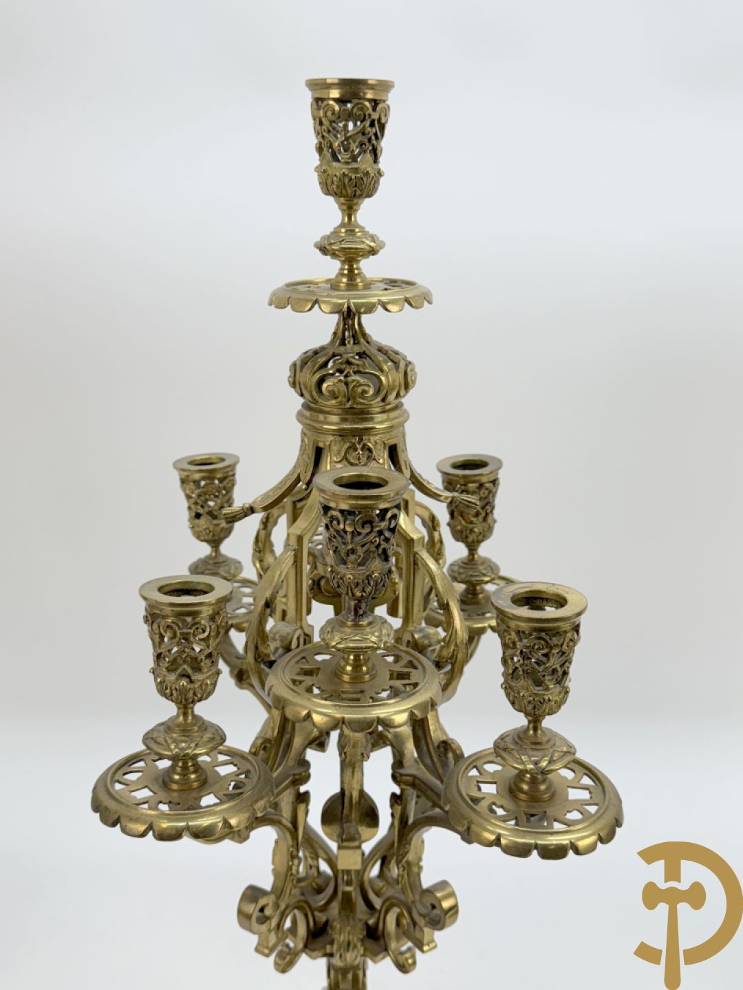 Driedelige bronzen vergulde garntiuur bestaande uit klok met medusahoofden en sfinxen, geflankeerd door paar zevenarmige kandelaars met accanthusranken en sfinxen