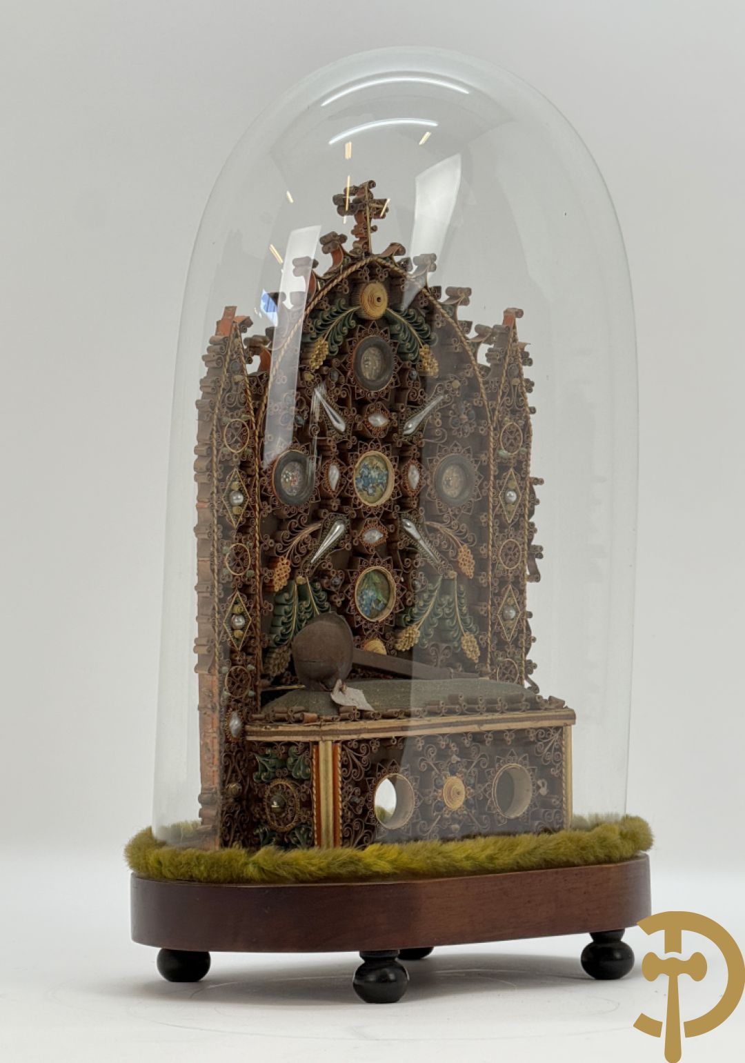 Relikwiehouder in de vorm van een altaar met Christusnagel en omgeven door papperollen - onder stolp