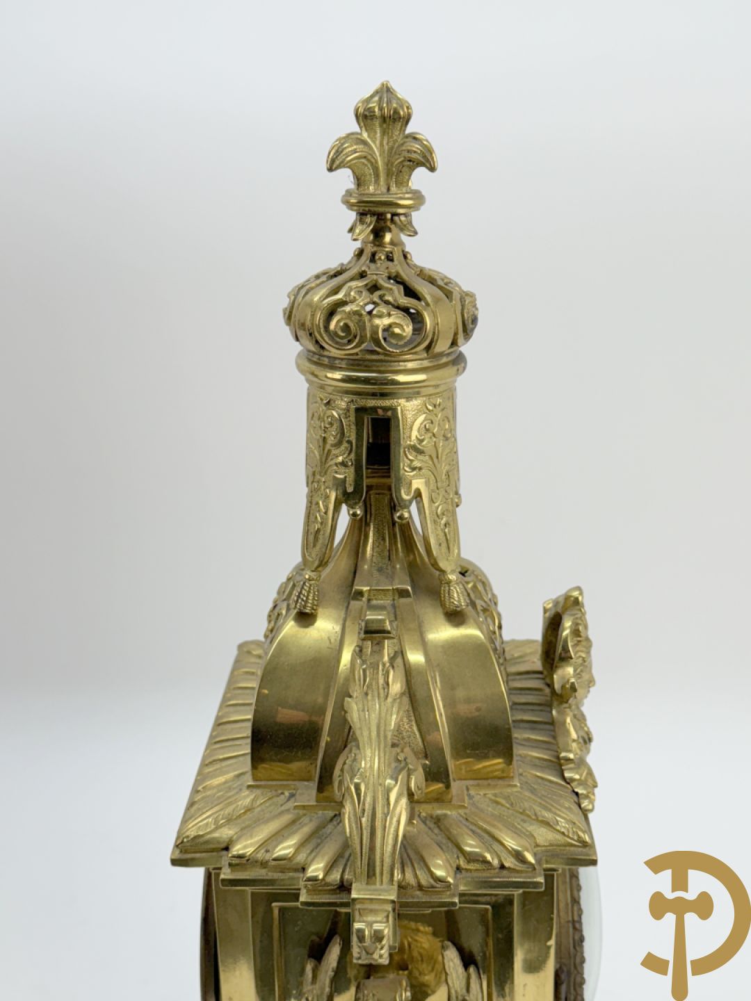 Driedelige bronzen vergulde garntiuur bestaande uit klok met medusahoofden en sfinxen, geflankeerd door paar zevenarmige kandelaars met accanthusranken en sfinxen