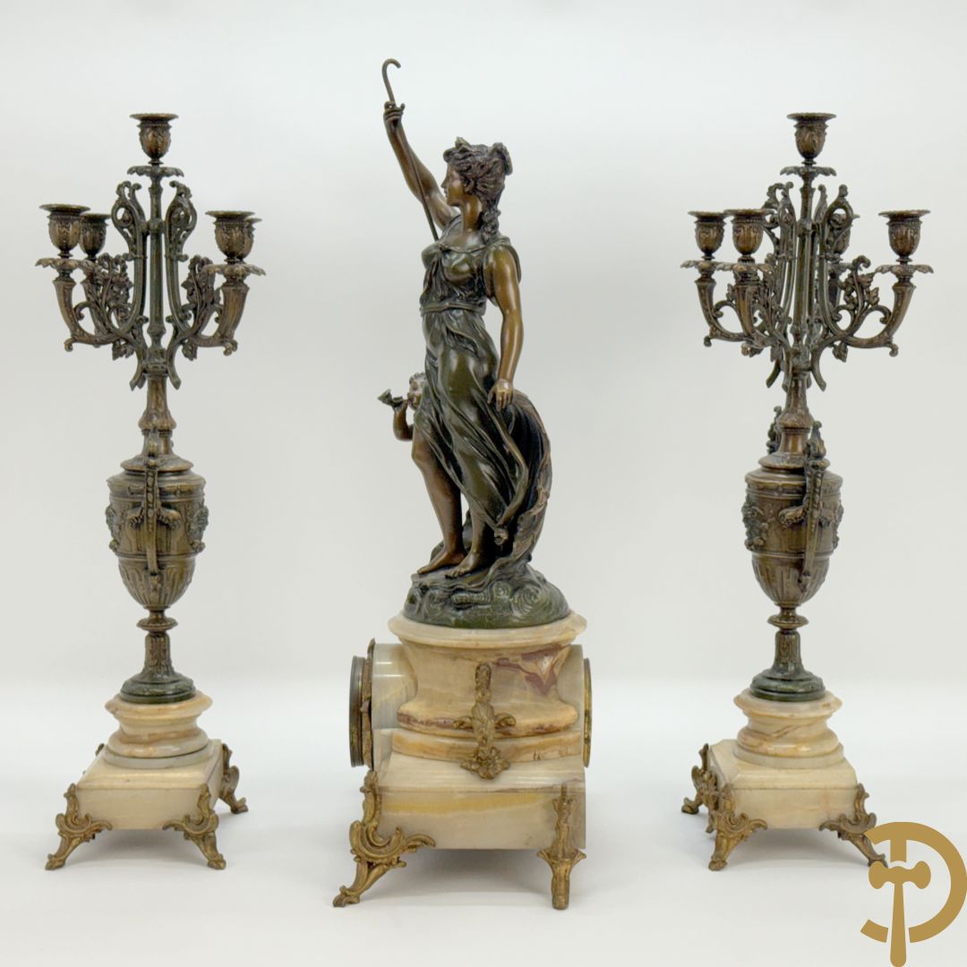 Driedelige zamak garnituur bestaande uit pendule met cupido en dame geflankeerd door paar vijfarmige kandelaars, Bruchon getekend