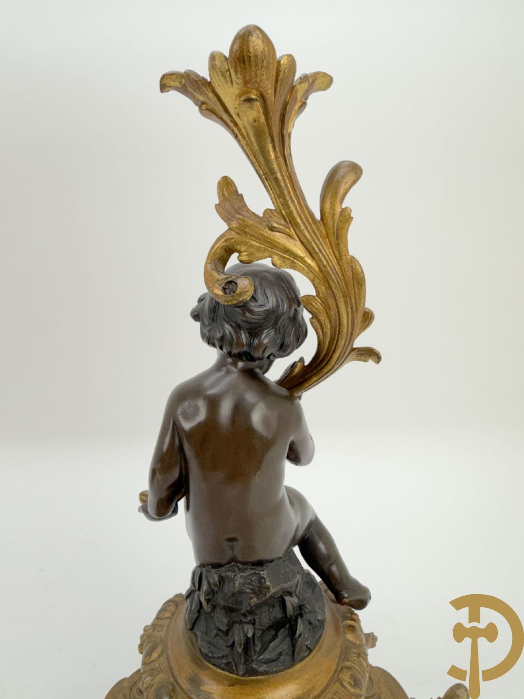 Driedelige bronzen garnituur bestaande uit middenstuk met bronzen vuurvergulde klok, Daubrée gemerkt à Nancy, bovenaan bekroond met Cleopatra met drinkbeker - getekend van Cumberworth sculpteur - geflankeerd door paar cupido