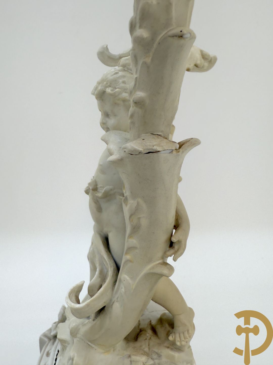 Driedelige porseleinen garnituur bestaande uit pendule bezet met lieftallig koppel, geflankeerd door paar kandelaars met cupido