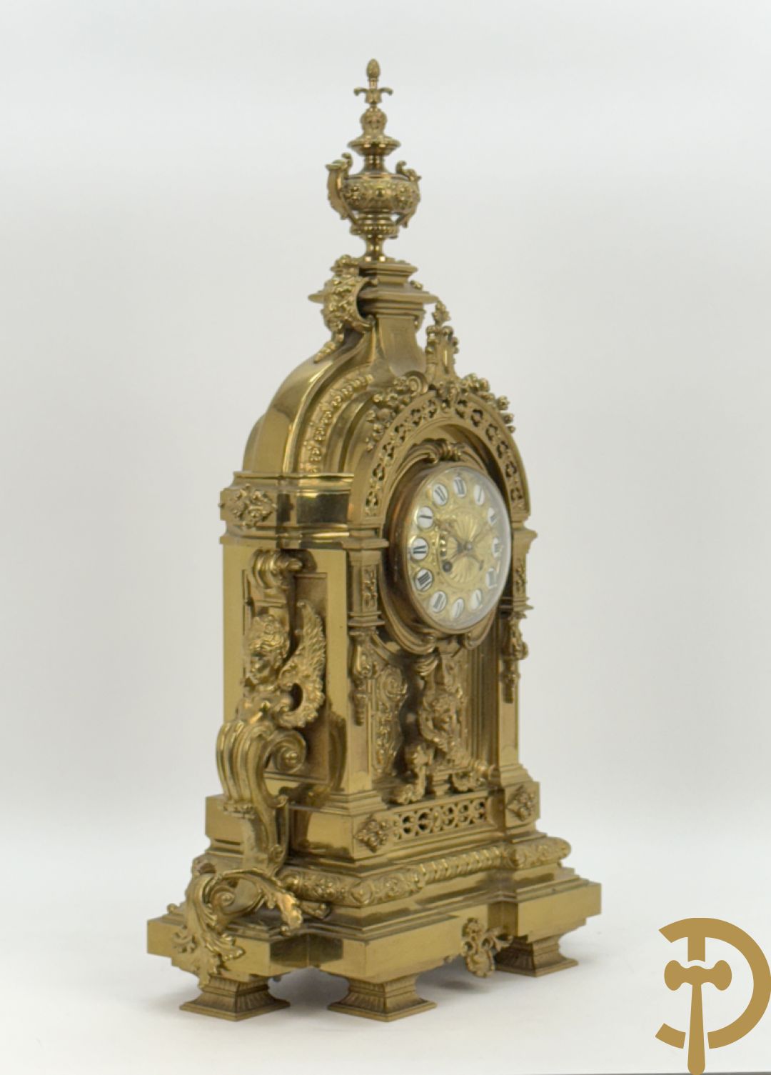 Vuurvergulde bronzen pendule, zijdelings bezet met gevleugelde dames, bovenaan met amfoor