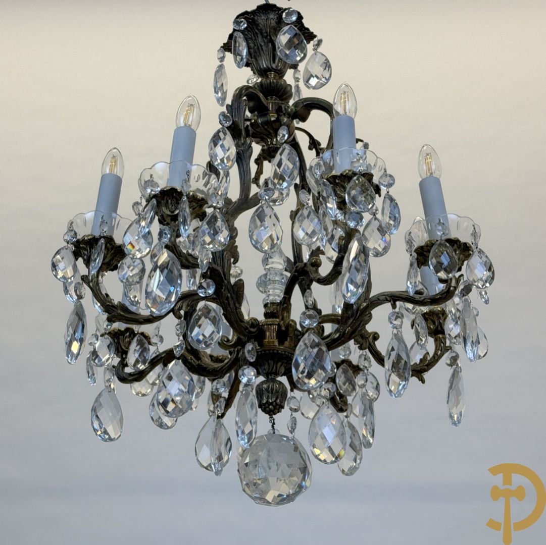 Achtarmige koperen luchter met kristallen bellen en binnenin met pinakel bezet