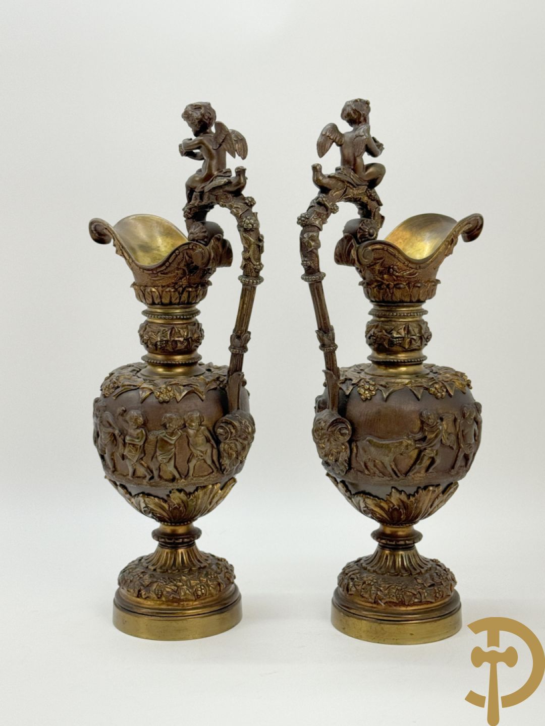 Paar bronzen schenkkannen met basrelief van putti en accanthusranken