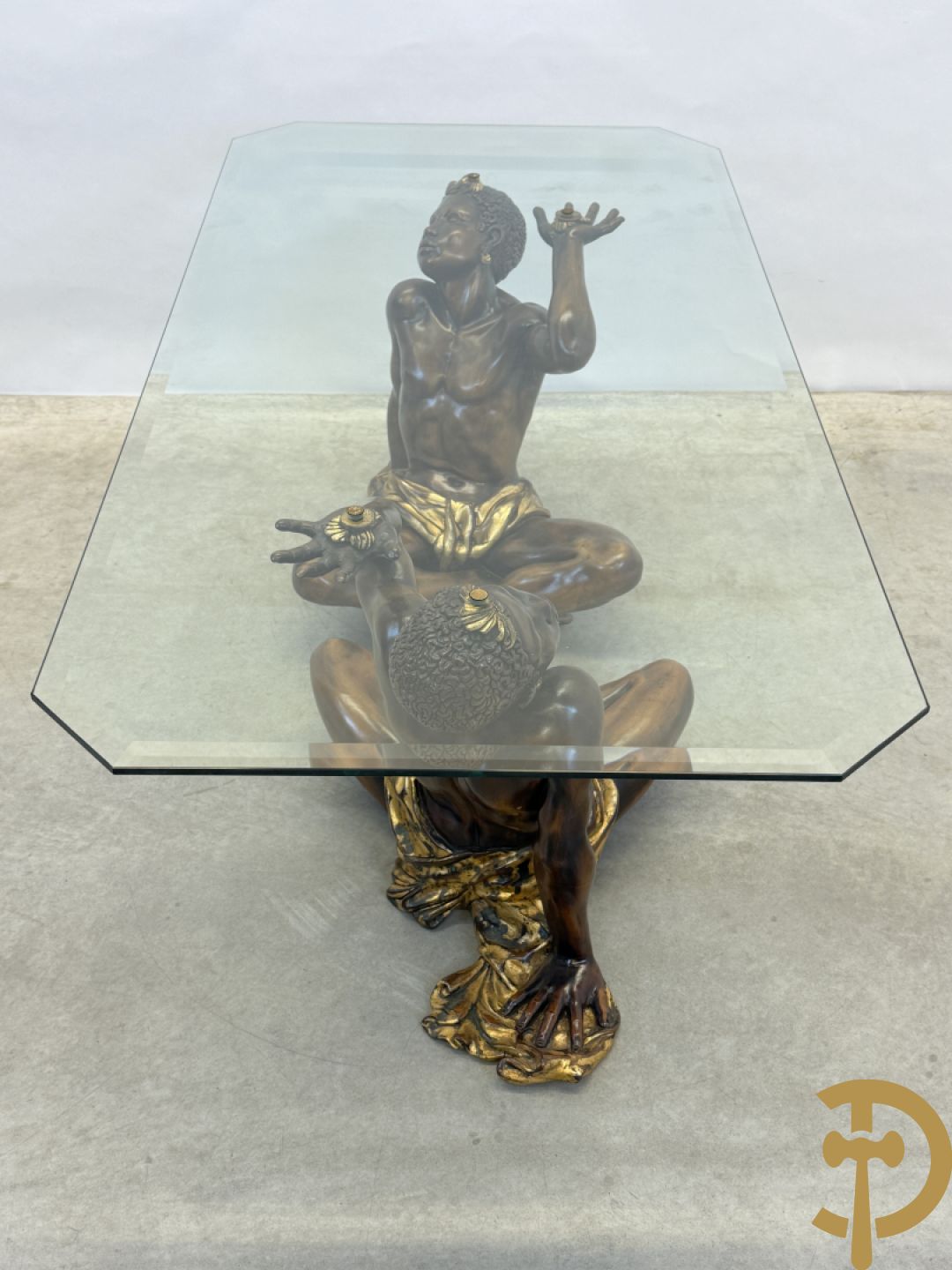 Salontafel met een paar moren met vergulde lendendoek dragende een achthoekig geslepen glazen blad