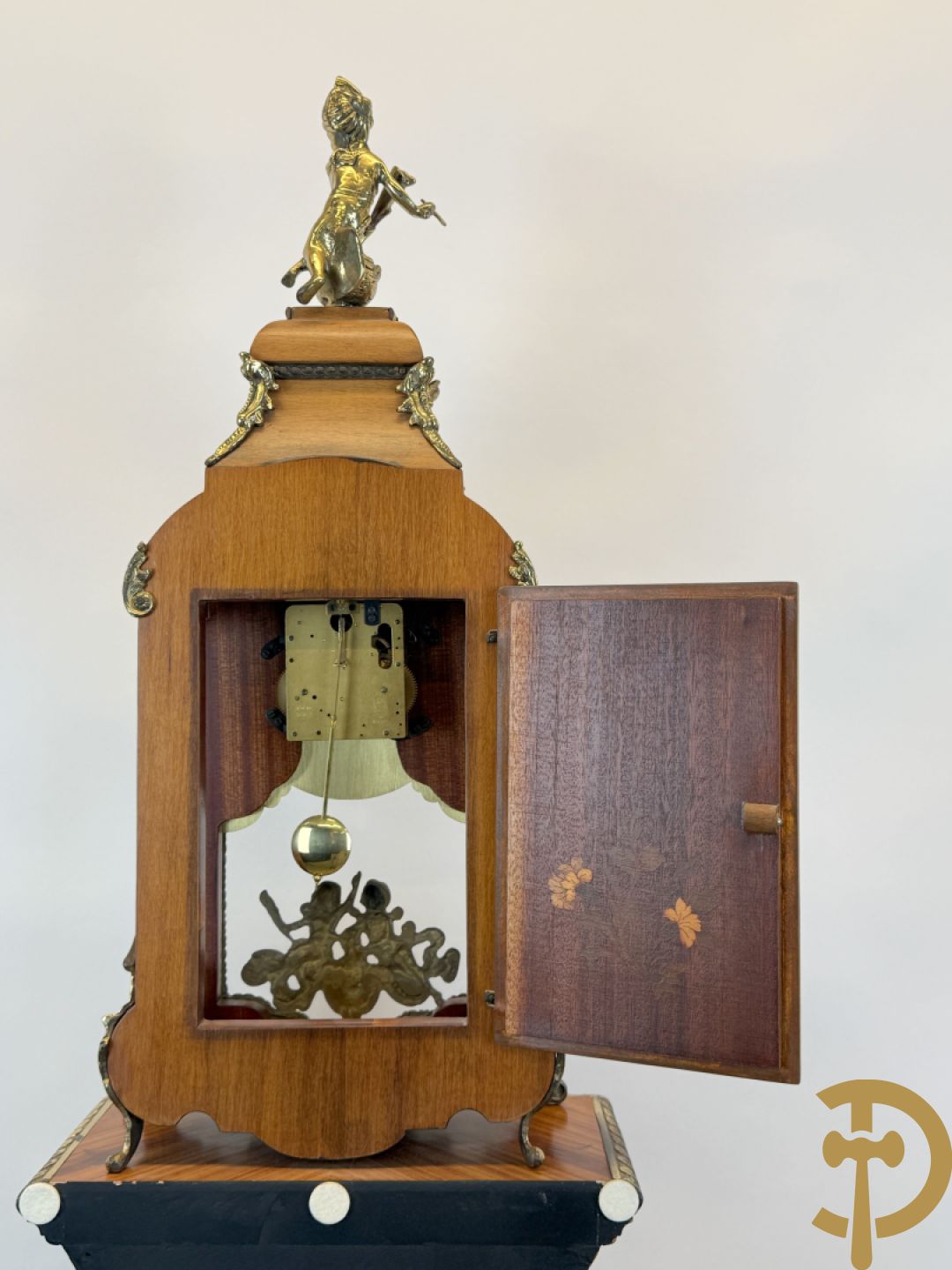 Notelaren pendule met bloemenmarquetterie en bronsbeslag, bovenaan bekroond met bronzen figuur - met bijhorende sokkel in notelaar met bronsbeslag