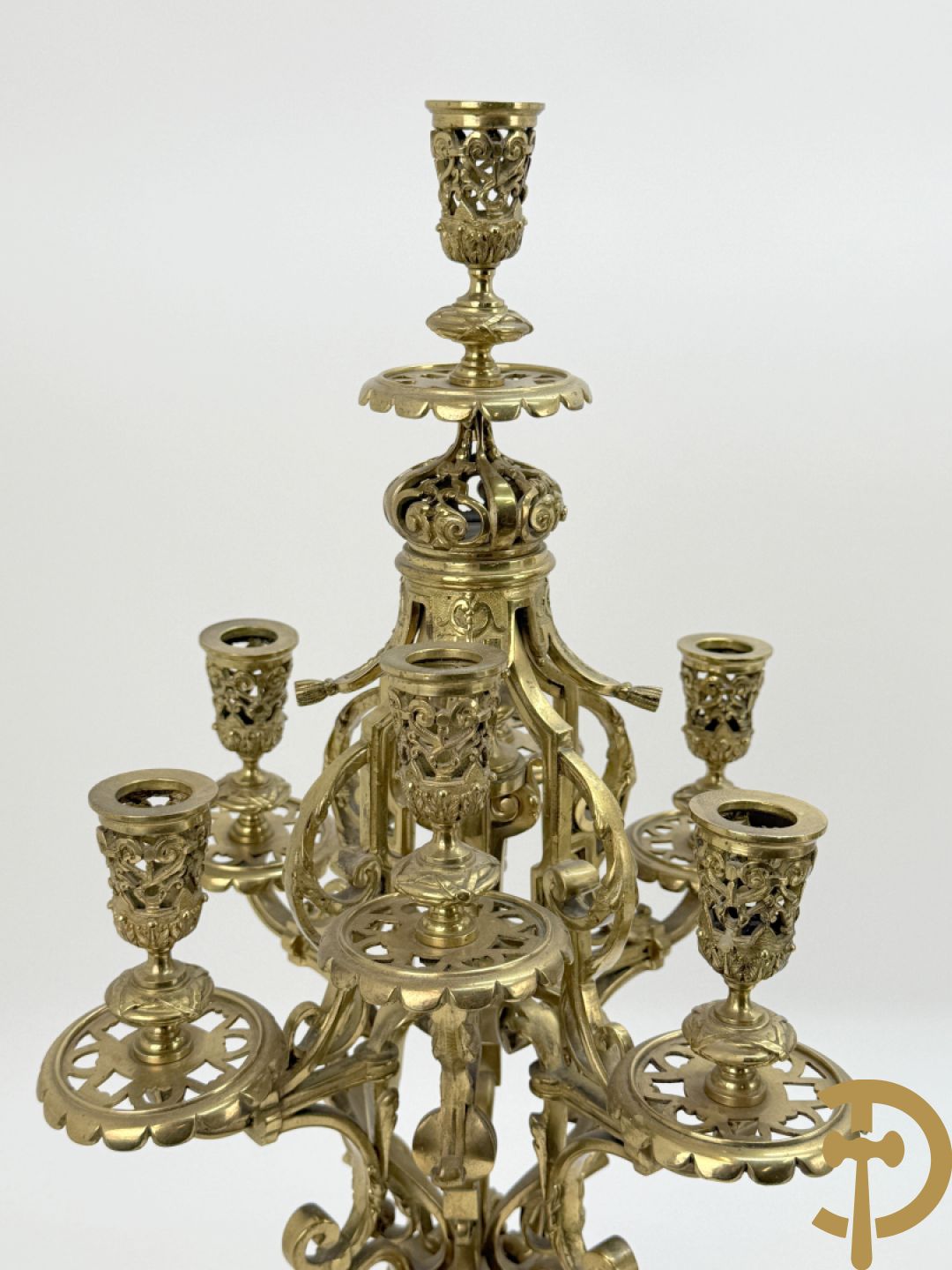 Driedelige bronzen vergulde garntiuur bestaande uit klok met medusahoofden en sfinxen, geflankeerd door paar zevenarmige kandelaars met accanthusranken en sfinxen