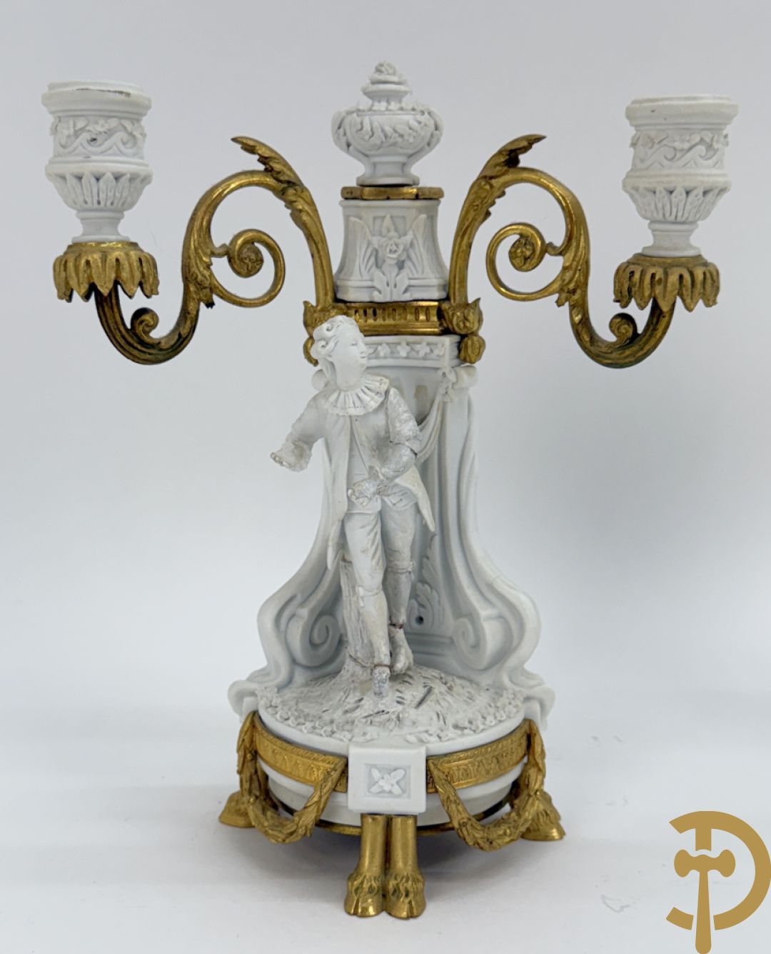 Driedelige porseleinen garnituur met bronsbeslag bestaande uit pendule met dame en amfoor geflankeerd door paar kandelaars bezet met personages