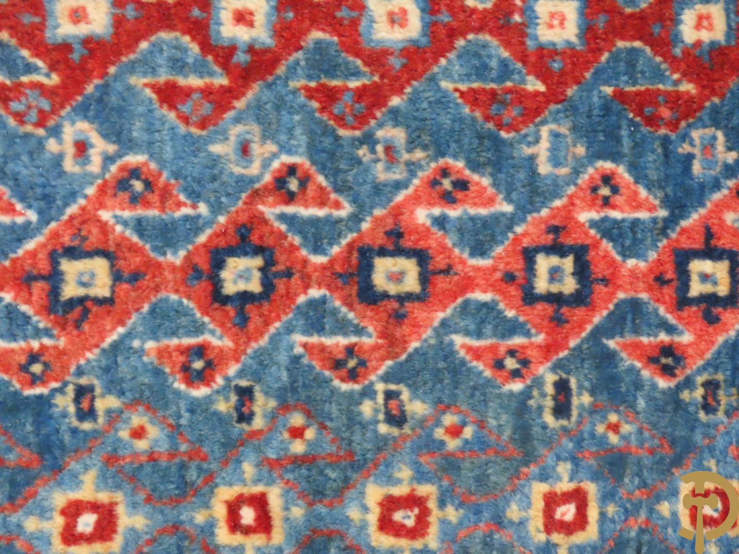 Oosters handgeknoopt tapijt met geometrische patronen op blauwe fond