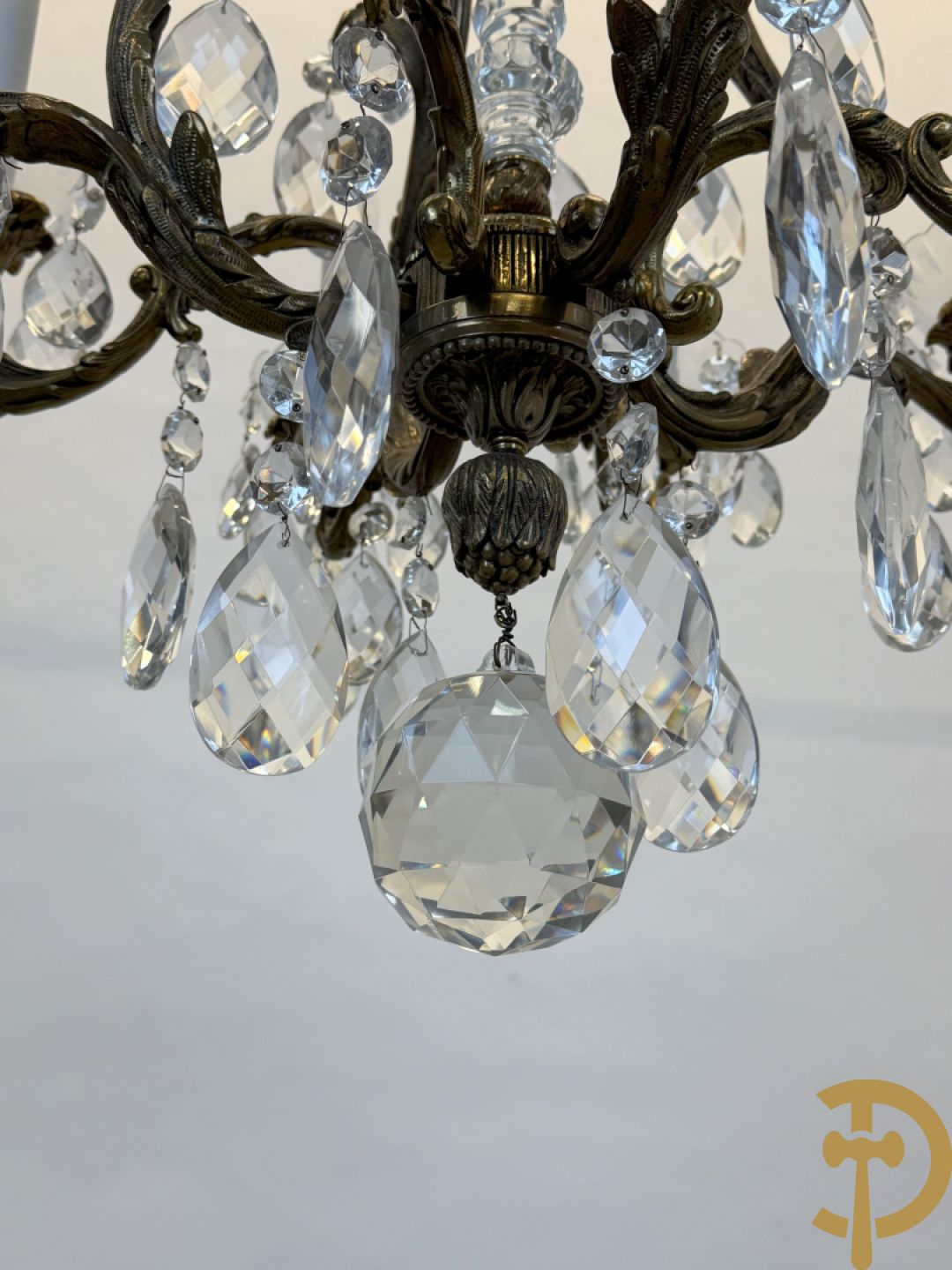 Achtarmige koperen luchter met kristallen bellen en binnenin met pinakel bezet