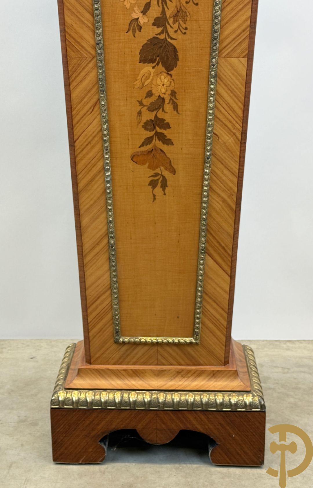 Notelaren pendule met bloemenmarquetterie en bronsbeslag, bovenaan bekroond met bronzen figuur - met bijhorende sokkel in notelaar met bronsbeslag