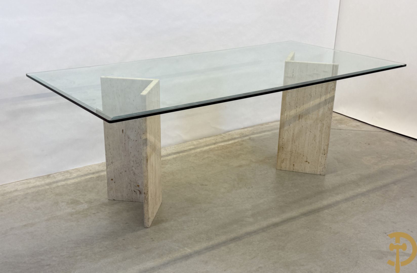 Moderne tafel met geslepen glazen blad op 2 travertin steunen