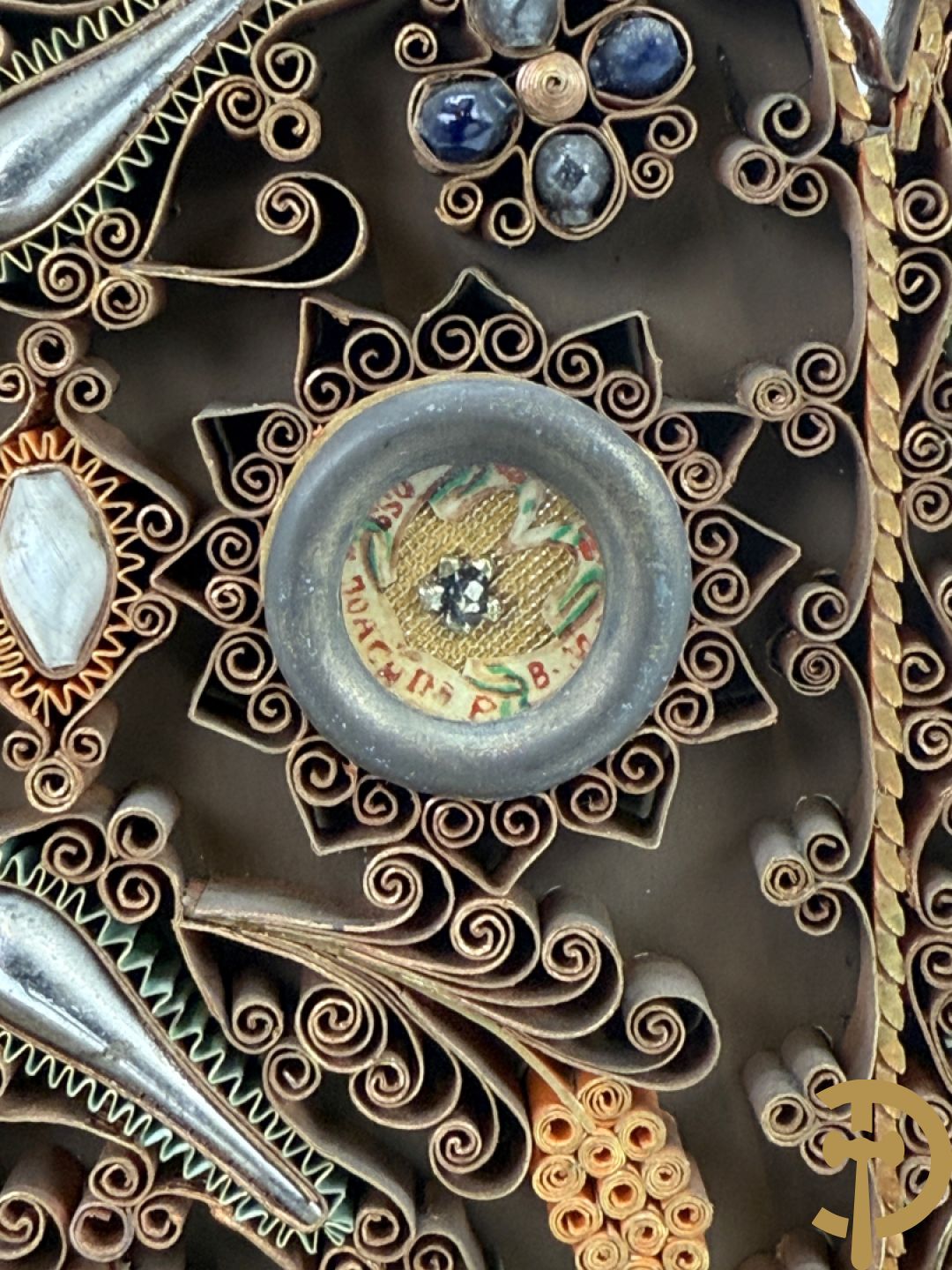 Relikwiehouder in de vorm van een altaar met Christusnagel en omgeven door papperollen - onder stolp