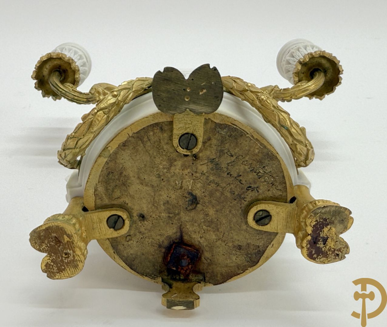 Driedelige porseleinen garnituur met bronsbeslag bestaande uit pendule met dame en amfoor geflankeerd door paar kandelaars bezet met personages