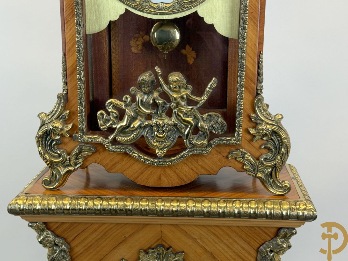 Notelaren pendule met bloemenmarquetterie en bronsbeslag, bovenaan bekroond met bronzen figuur - met bijhorende sokkel in notelaar met bronsbeslag