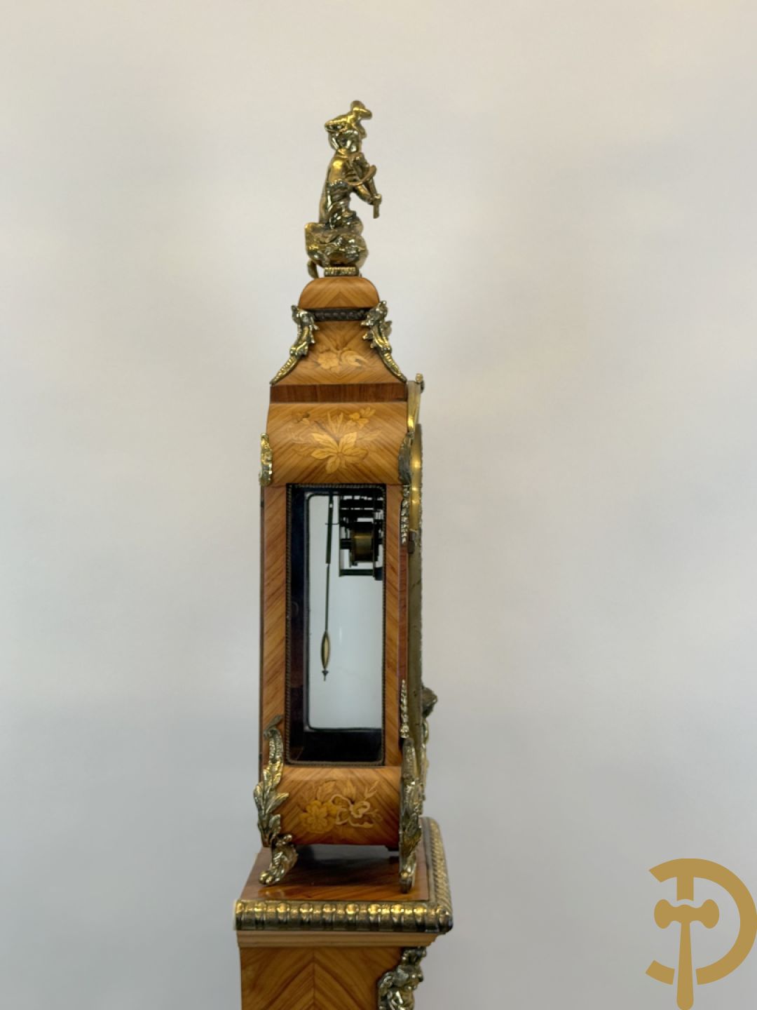 Notelaren pendule met bloemenmarquetterie en bronsbeslag, bovenaan bekroond met bronzen figuur - met bijhorende sokkel in notelaar met bronsbeslag