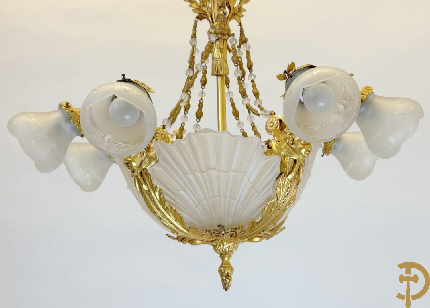 Bronzen vuurvergulde luchter met 4 paar lichtpunten bezet met bladranken, onderaan met glazen schelpen en armen bezet met cupidohoofden