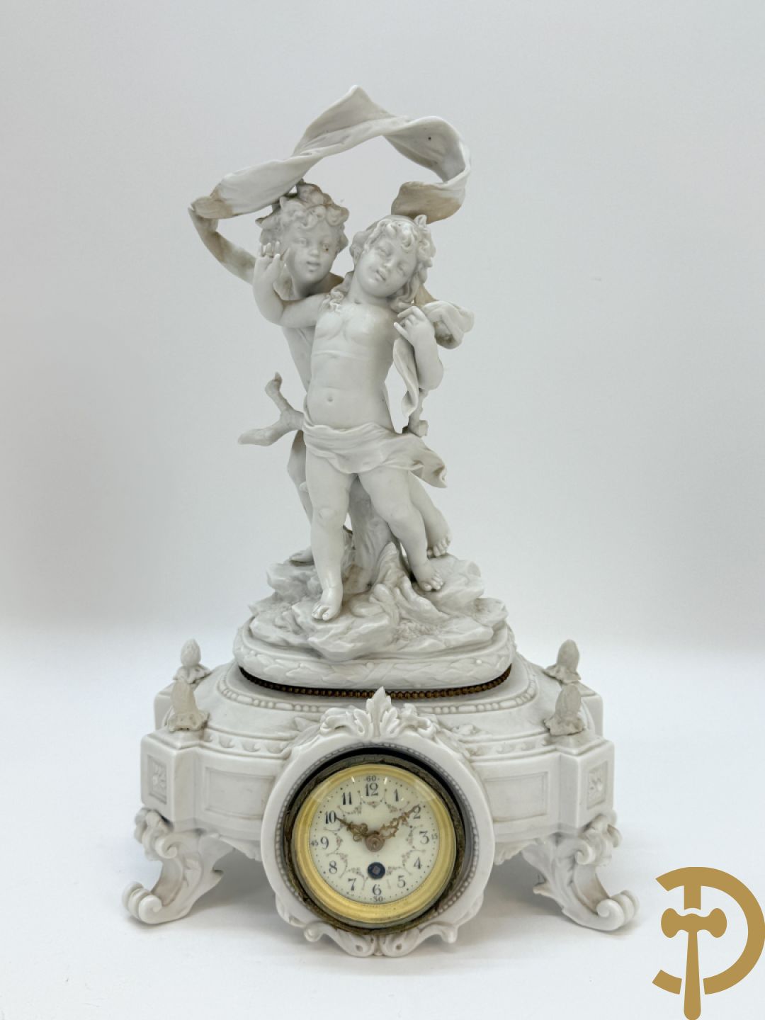 Driedelige porseleinen garnituur bestaande uit pendule bezet met lieftallig koppel, geflankeerd door paar kandelaars met cupido