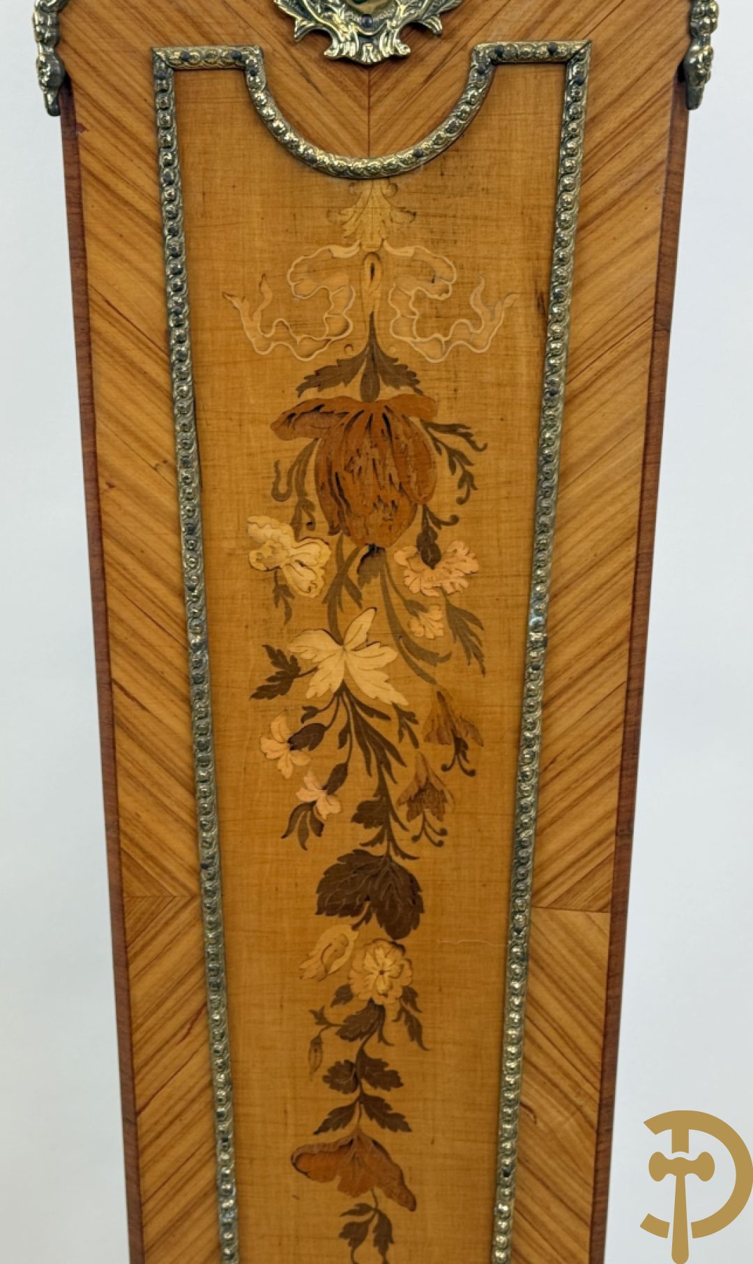 Notelaren pendule met bloemenmarquetterie en bronsbeslag, bovenaan bekroond met bronzen figuur - met bijhorende sokkel in notelaar met bronsbeslag