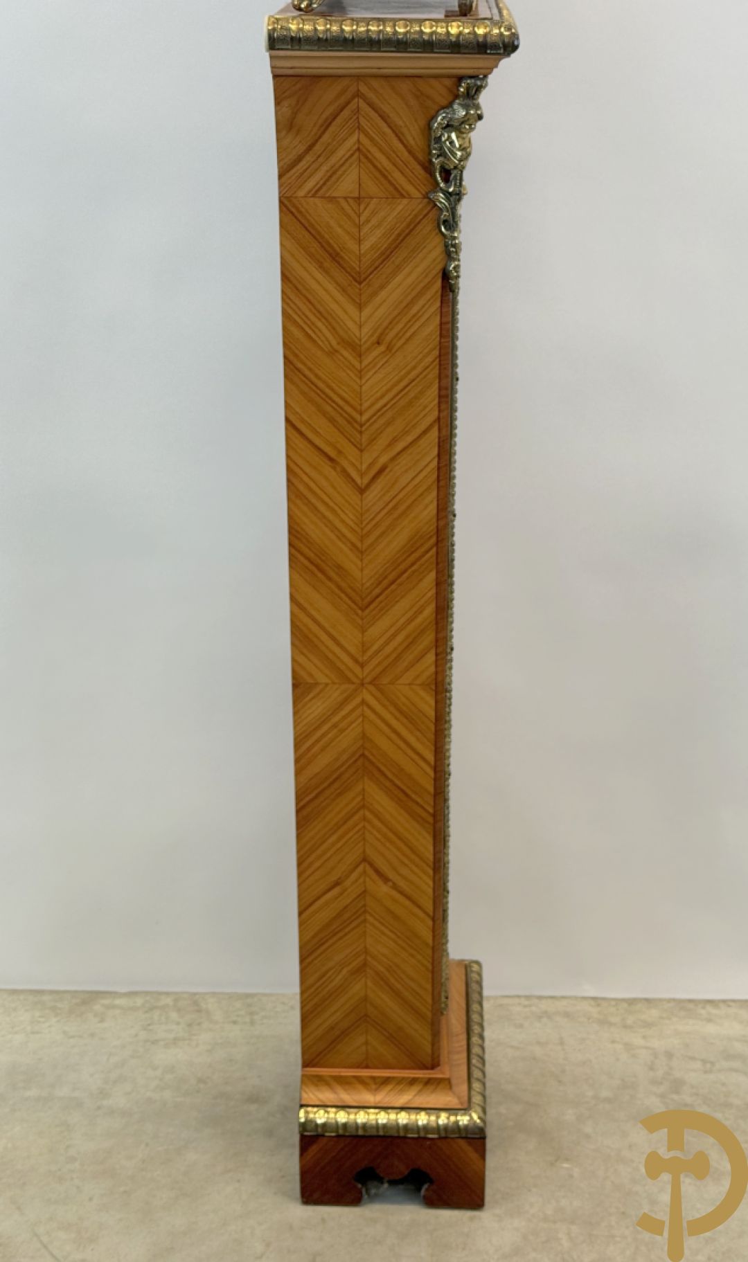 Notelaren pendule met bloemenmarquetterie en bronsbeslag, bovenaan bekroond met bronzen figuur - met bijhorende sokkel in notelaar met bronsbeslag