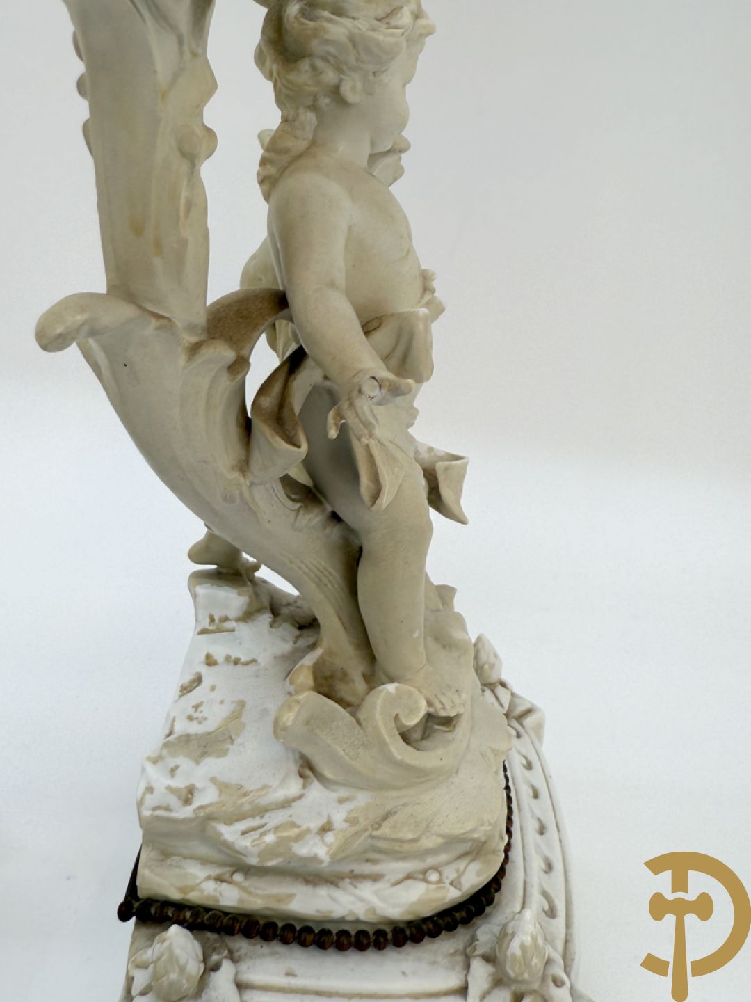 Driedelige porseleinen garnituur bestaande uit pendule bezet met lieftallig koppel, geflankeerd door paar kandelaars met cupido