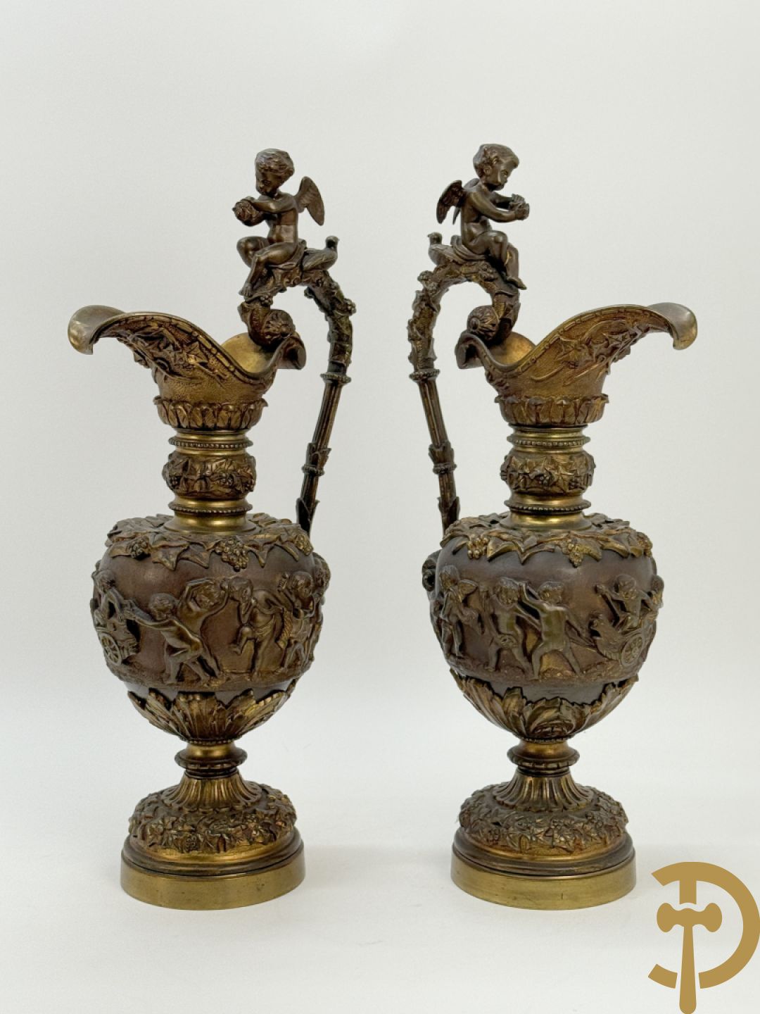 Paar bronzen schenkkannen met basrelief van putti en accanthusranken