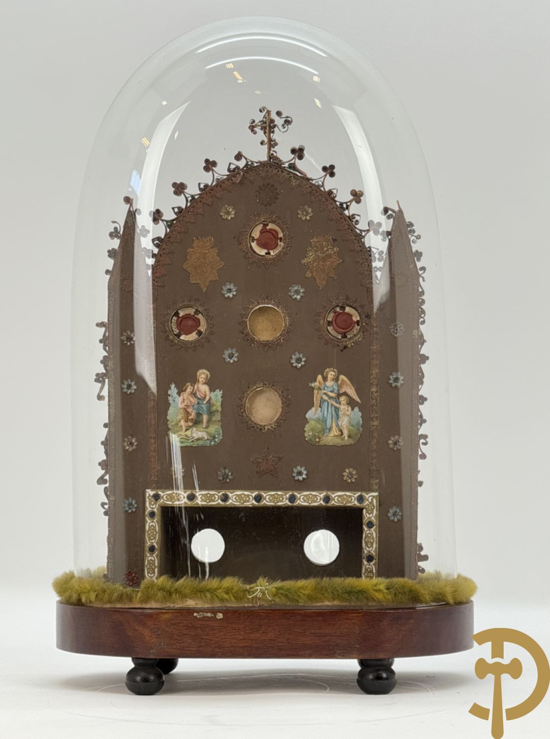 Relikwiehouder in de vorm van een altaar met Christusnagel en omgeven door papperollen - onder stolp