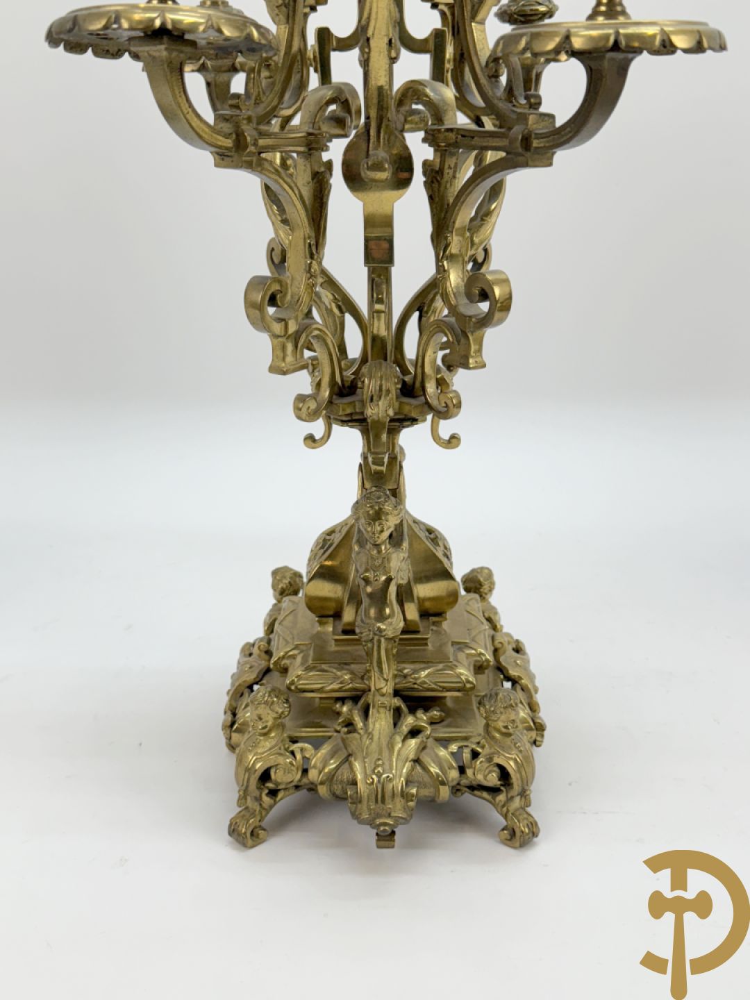 Driedelige bronzen vergulde garntiuur bestaande uit klok met medusahoofden en sfinxen, geflankeerd door paar zevenarmige kandelaars met accanthusranken en sfinxen