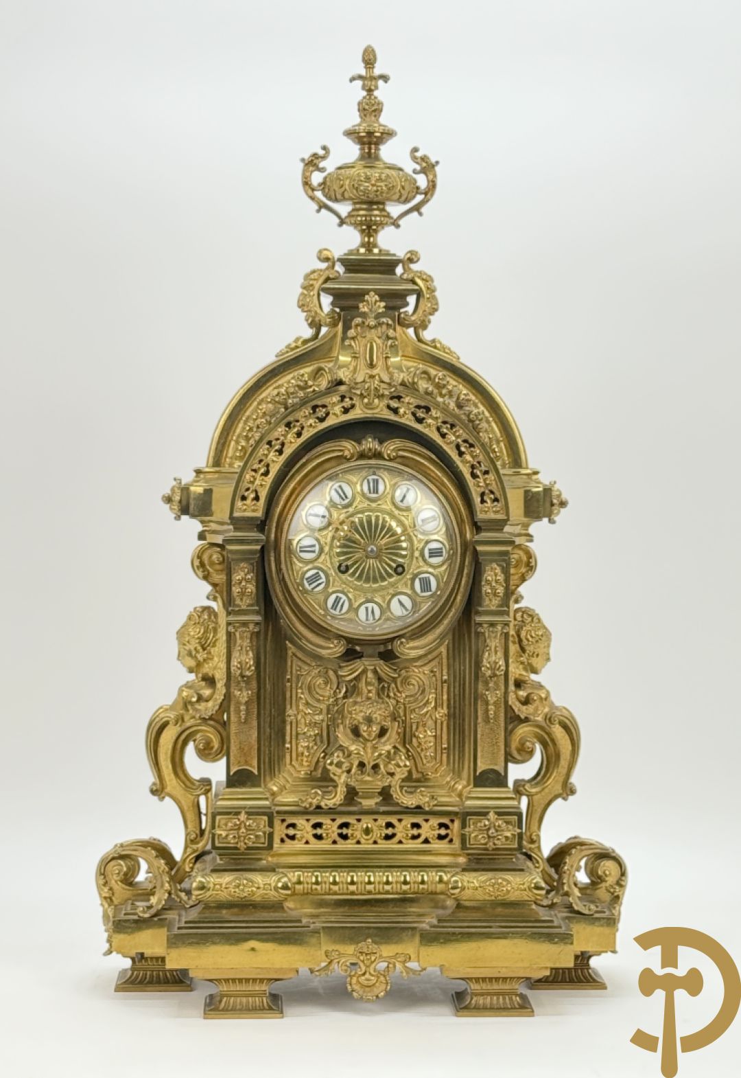 Vuurvergulde bronzen pendule, zijdelings bezet met gevleugelde dames, bovenaan met amfoor