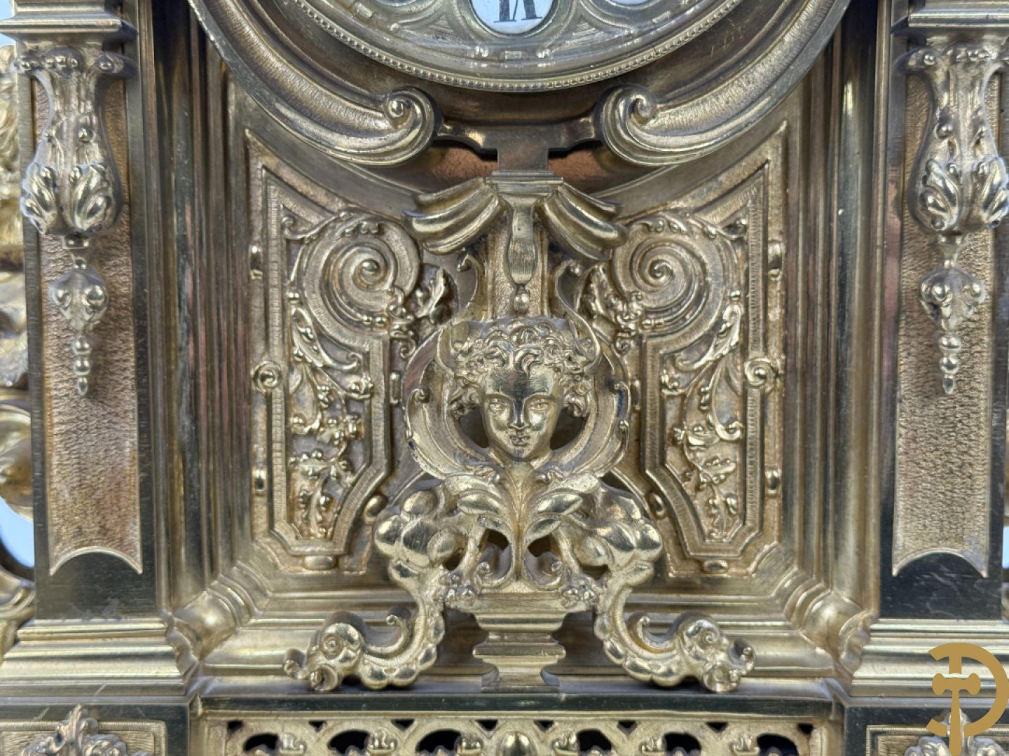 Vuurvergulde bronzen pendule, zijdelings bezet met gevleugelde dames, bovenaan met amfoor