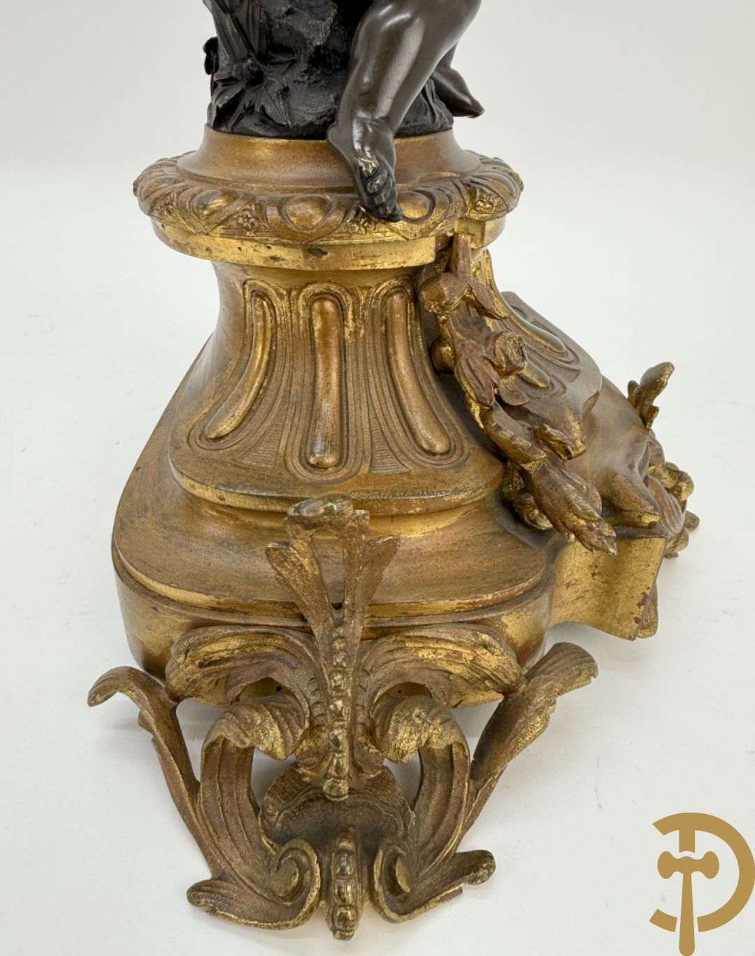 Driedelige bronzen garnituur bestaande uit middenstuk met bronzen vuurvergulde klok, Daubrée gemerkt à Nancy, bovenaan bekroond met Cleopatra met drinkbeker - getekend van Cumberworth sculpteur - geflankeerd door paar cupido