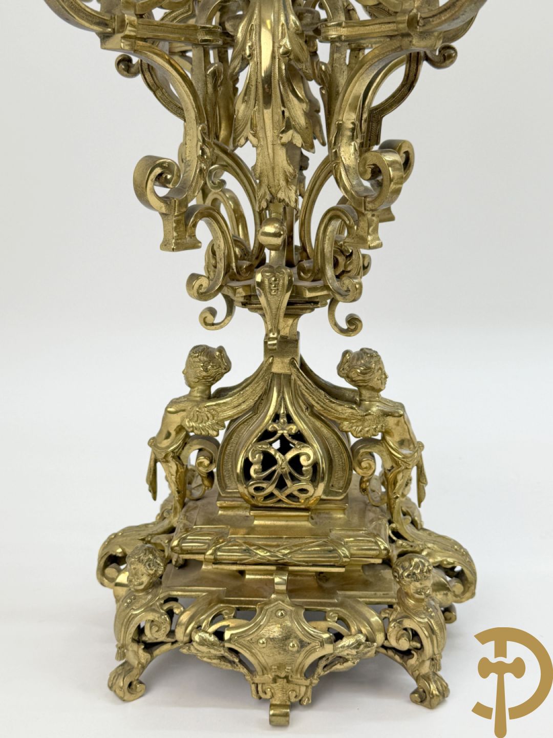 Driedelige bronzen vergulde garntiuur bestaande uit klok met medusahoofden en sfinxen, geflankeerd door paar zevenarmige kandelaars met accanthusranken en sfinxen