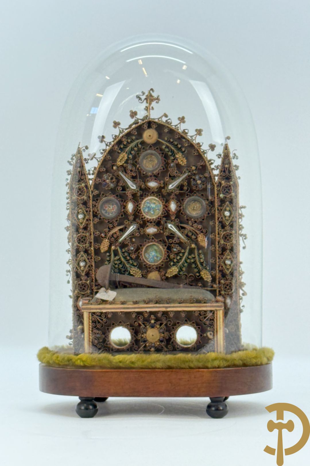 Relikwiehouder in de vorm van een altaar met Christusnagel en omgeven door papperollen - onder stolp