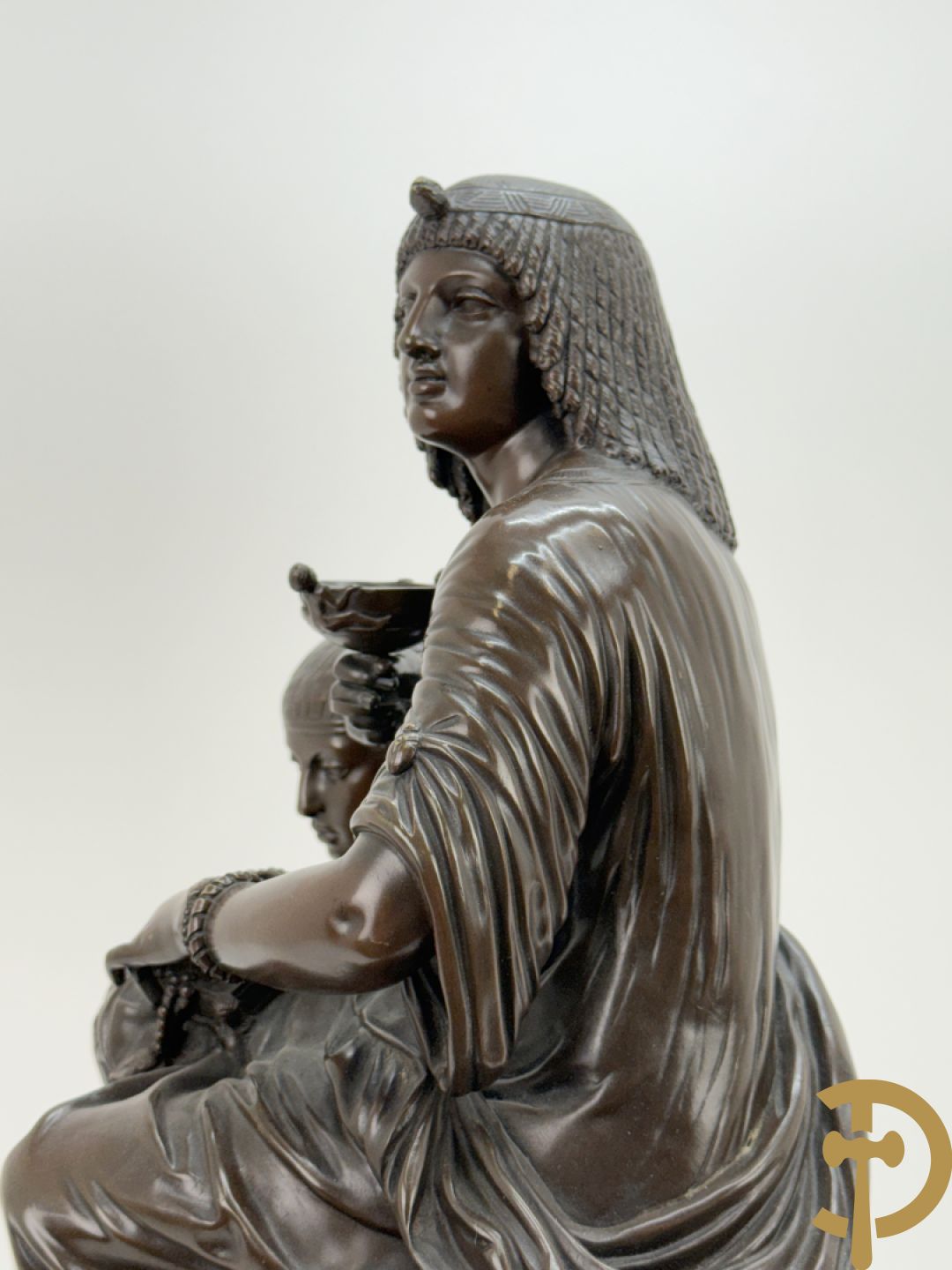 Driedelige bronzen garnituur bestaande uit middenstuk met bronzen vuurvergulde klok, Daubrée gemerkt à Nancy, bovenaan bekroond met Cleopatra met drinkbeker - getekend van Cumberworth sculpteur - geflankeerd door paar cupido