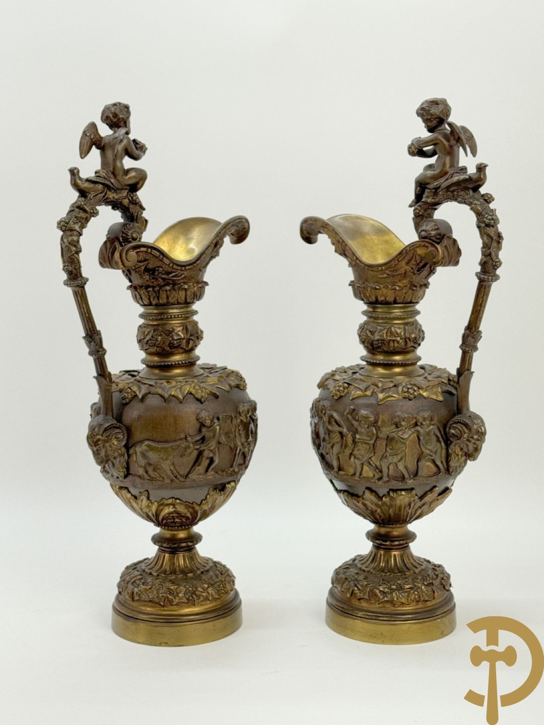Paar bronzen schenkkannen met basrelief van putti en accanthusranken