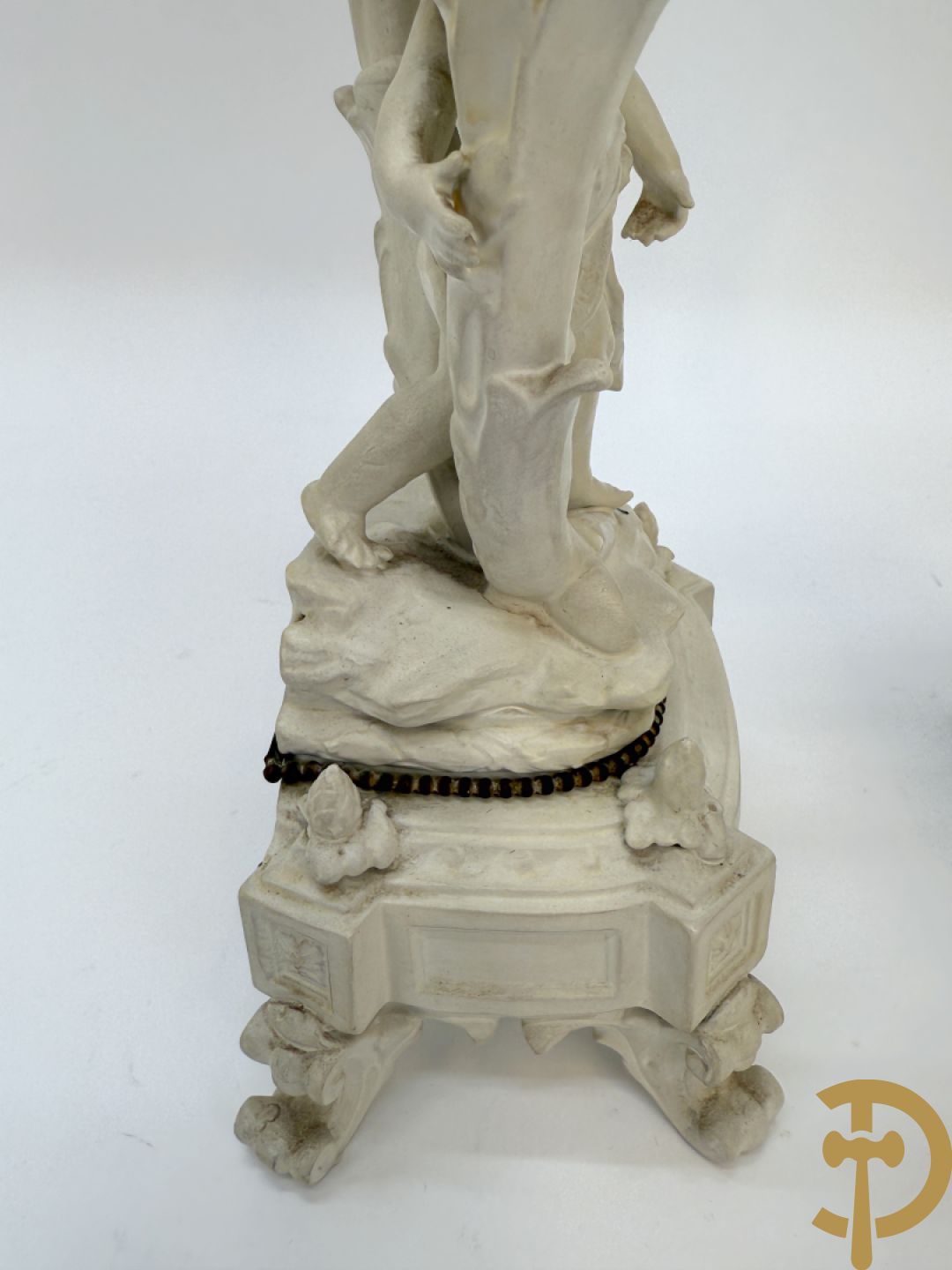 Driedelige porseleinen garnituur bestaande uit pendule bezet met lieftallig koppel, geflankeerd door paar kandelaars met cupido