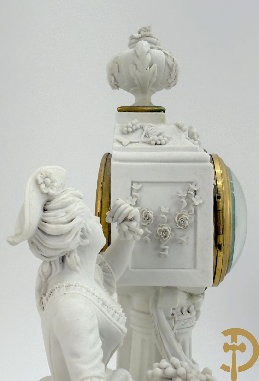 Driedelige porseleinen garnituur met bronsbeslag bestaande uit pendule met dame en amfoor geflankeerd door paar kandelaars bezet met personages