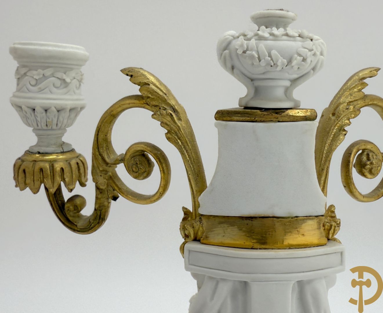 Driedelige porseleinen garnituur met bronsbeslag bestaande uit pendule met dame en amfoor geflankeerd door paar kandelaars bezet met personages