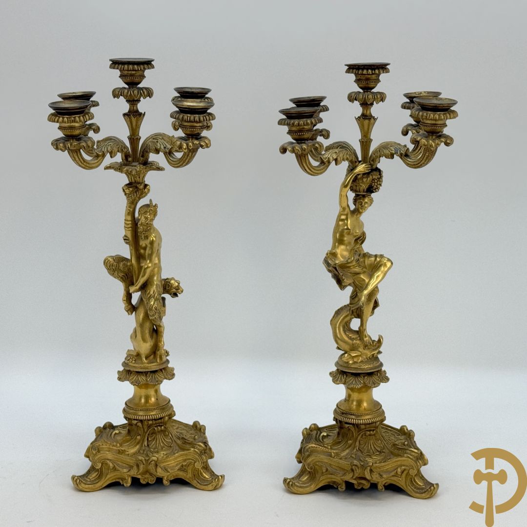 Paar bronzen kandelaars met sater en naakte dame, versierd met accanthusranken en dierenmotieven