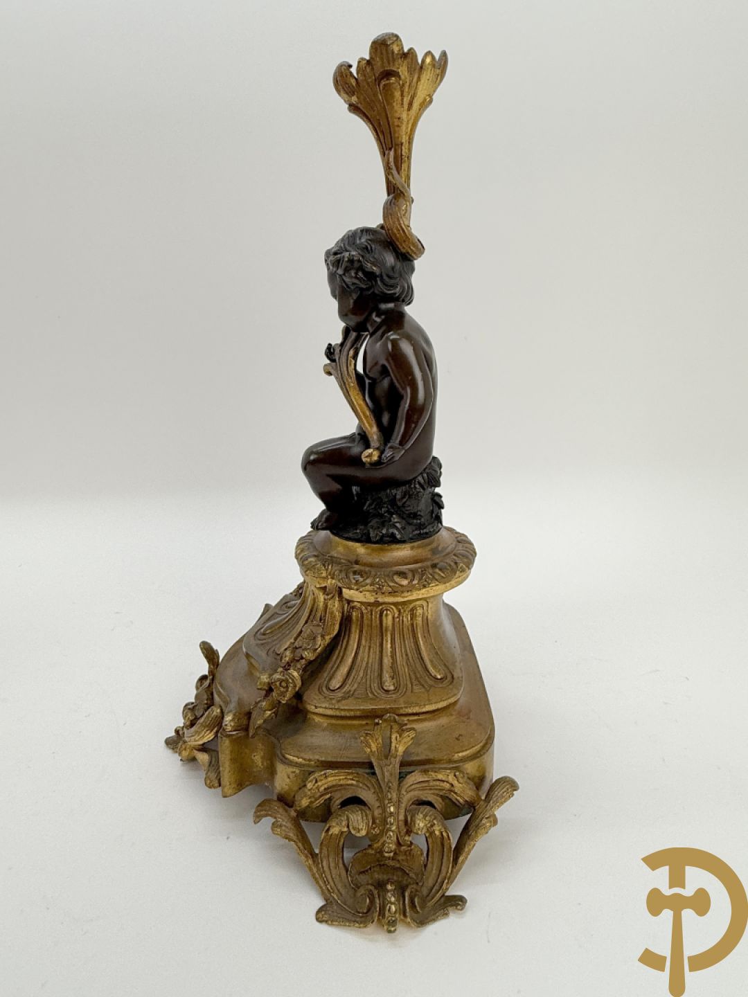 Driedelige bronzen garnituur bestaande uit middenstuk met bronzen vuurvergulde klok, Daubrée gemerkt à Nancy, bovenaan bekroond met Cleopatra met drinkbeker - getekend van Cumberworth sculpteur - geflankeerd door paar cupido