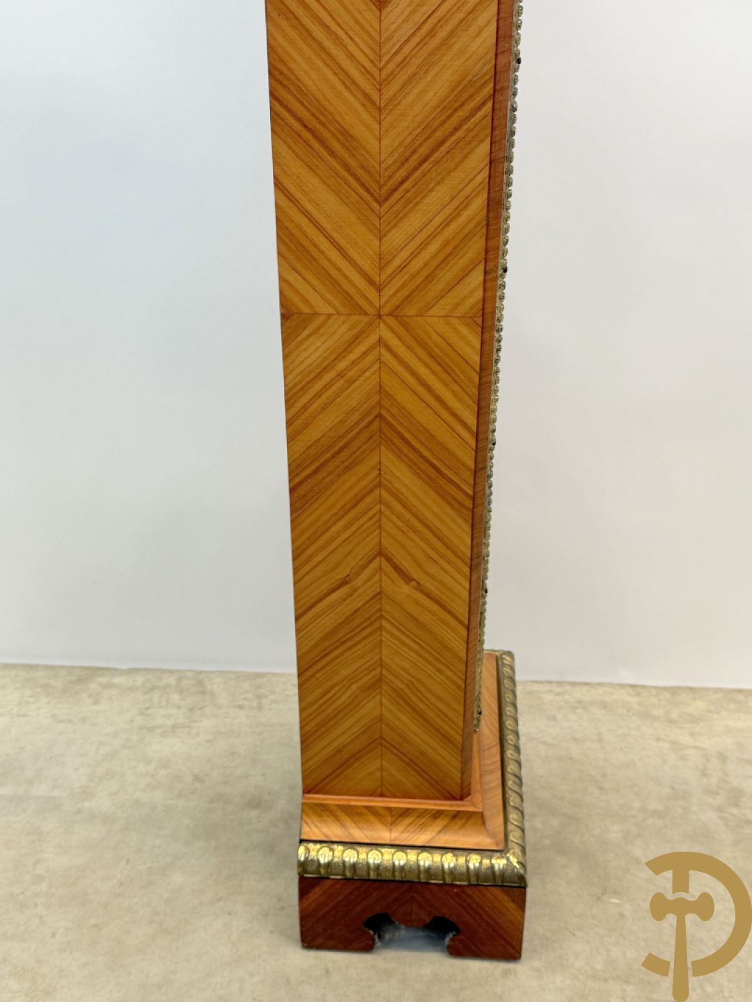 Notelaren pendule met bloemenmarquetterie en bronsbeslag, bovenaan bekroond met bronzen figuur - met bijhorende sokkel in notelaar met bronsbeslag