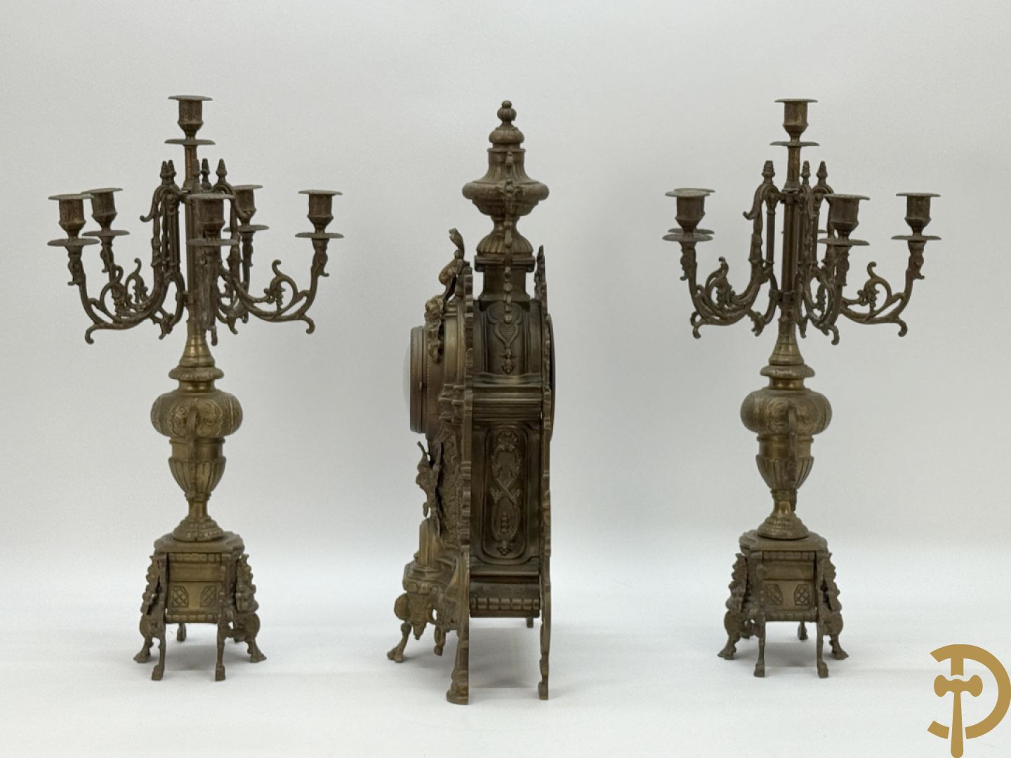 Driedelige koperen garnituur, klok geflankeerd door paar vijfarmige kandelaars