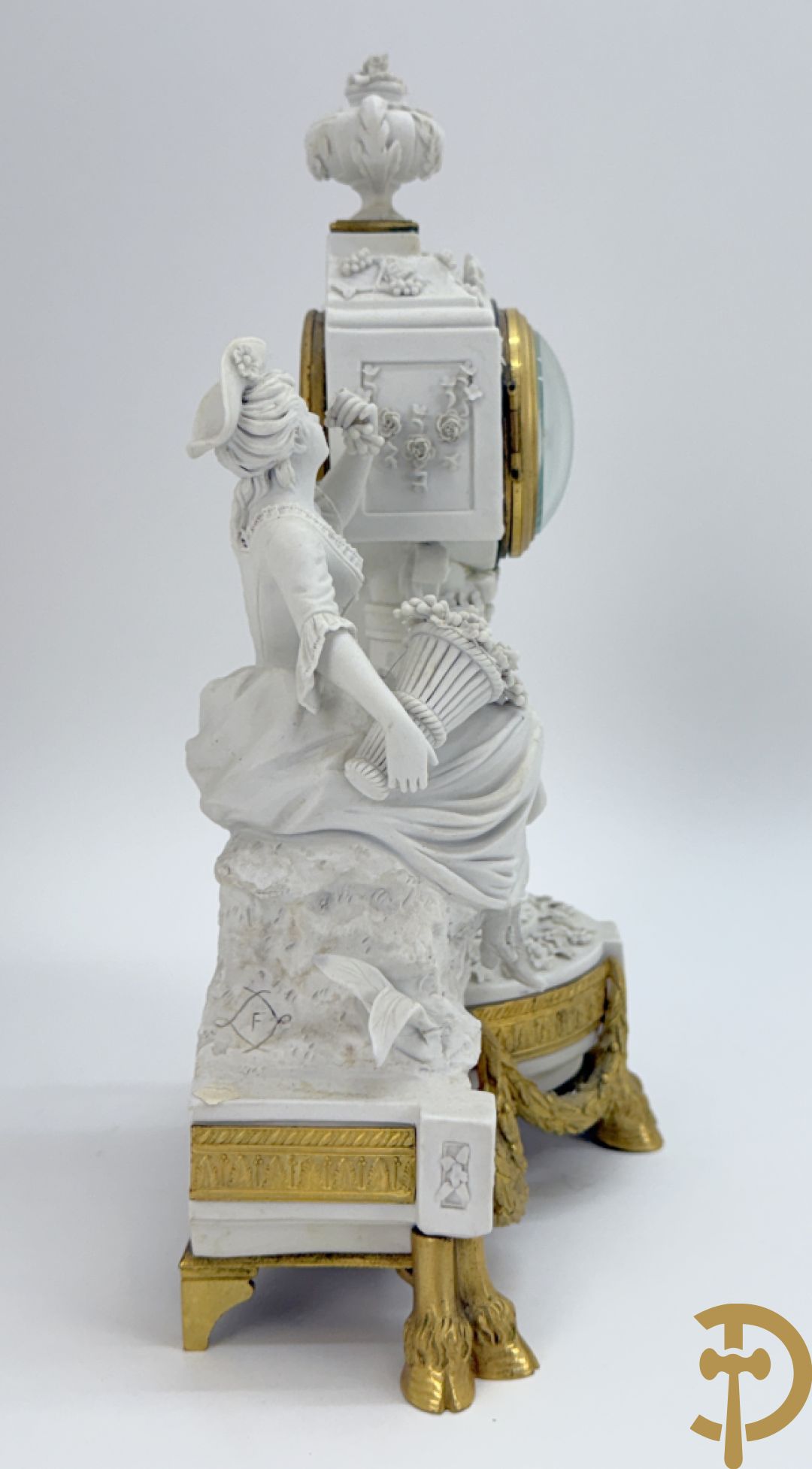 Driedelige porseleinen garnituur met bronsbeslag bestaande uit pendule met dame en amfoor geflankeerd door paar kandelaars bezet met personages