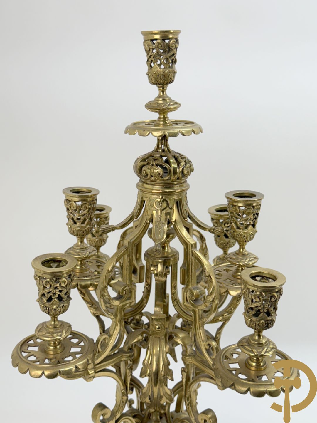 Driedelige bronzen vergulde garntiuur bestaande uit klok met medusahoofden en sfinxen, geflankeerd door paar zevenarmige kandelaars met accanthusranken en sfinxen