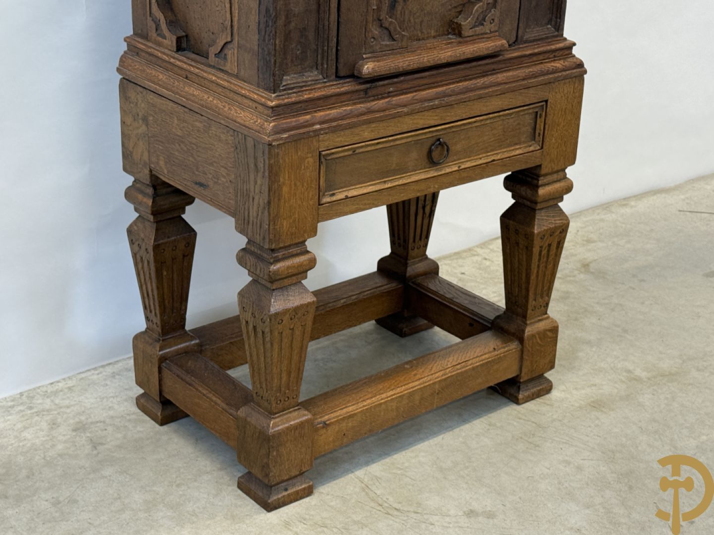 Massief eiken ééndeurskast op onderstel met lade bovenaan, lade onderaan, sculptuur in zijkant en deur