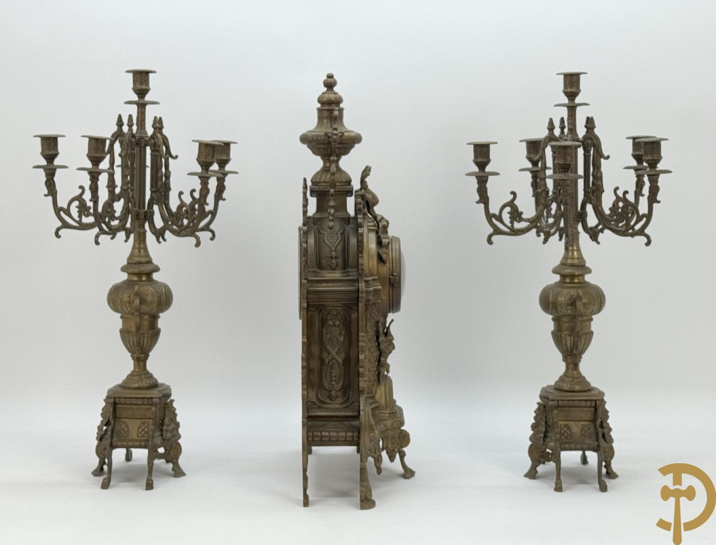 Driedelige koperen garnituur, klok geflankeerd door paar vijfarmige kandelaars