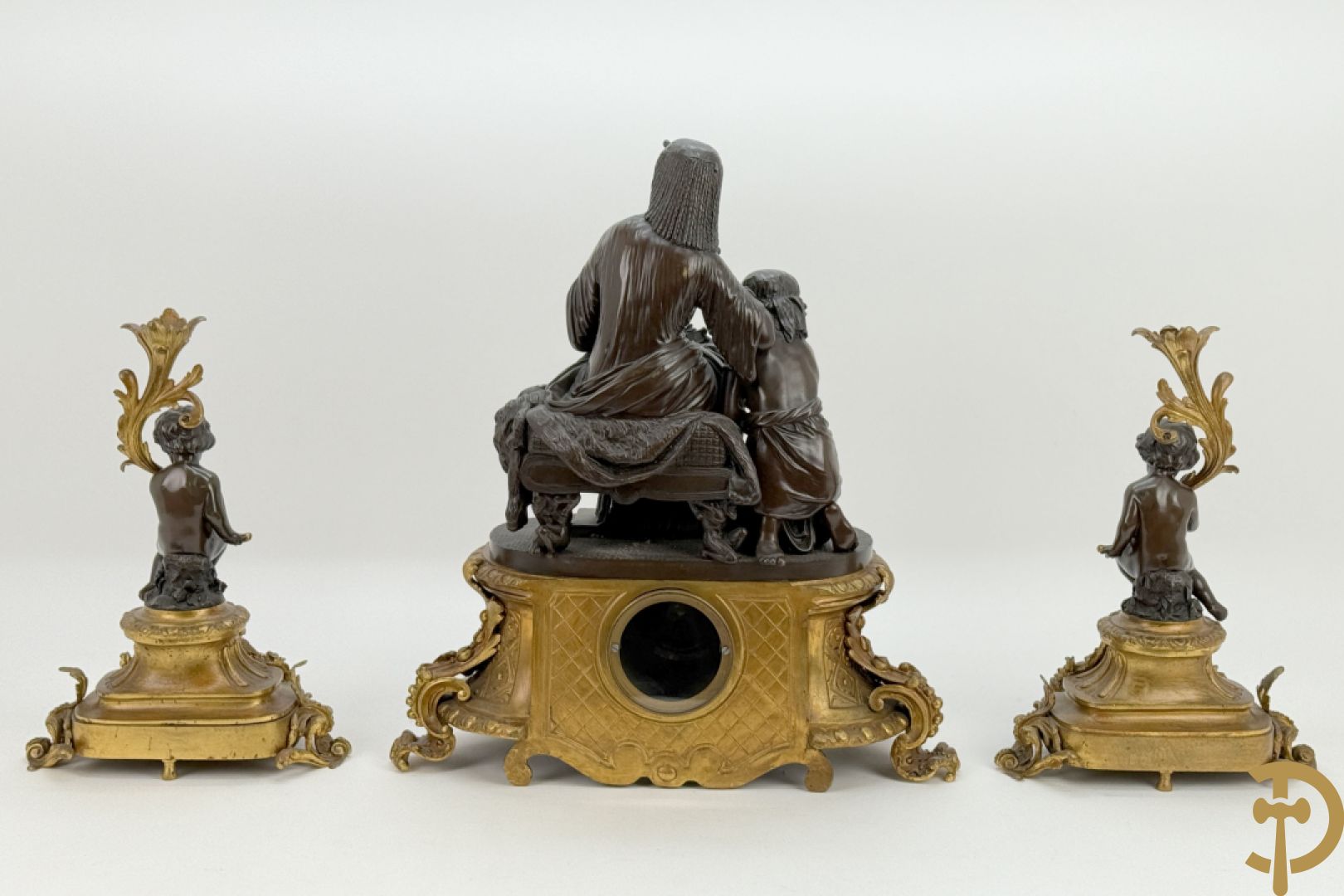 Driedelige bronzen garnituur bestaande uit middenstuk met bronzen vuurvergulde klok, Daubrée gemerkt à Nancy, bovenaan bekroond met Cleopatra met drinkbeker - getekend van Cumberworth sculpteur - geflankeerd door paar cupido